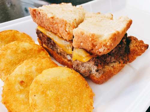A hearty sandwich with meat and cheese, served with crispy potato chips on the side.