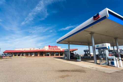 A travel center with a gas station and a restaurant under a clear blue sky.