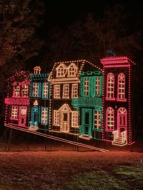 Colorful holiday lights form a whimsical house display against a dark night sky.