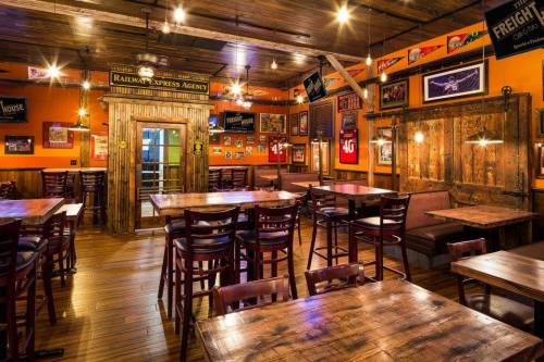 Cozy restaurant interior with wooden tables, warm lighting, and sports memorabilia on the walls.