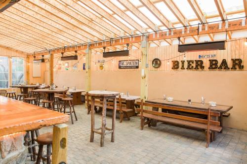 Interior of a rustic restaurant with wooden tables, benches, and a bar, featuring warm lighting and decorative signs.
