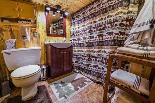 Cozy bathroom with wooden accents, a bear-themed shower curtain, and neatly stacked towels on a wooden shelf.