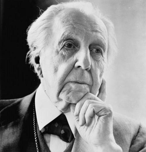 A thoughtful older man with white hair and a suit, resting his chin on his hand, gazing into the distance.