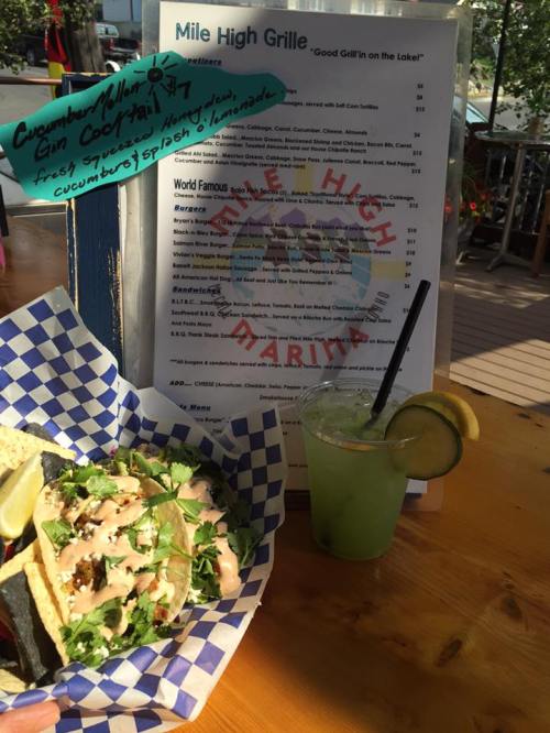 A plate of tacos with toppings next to a refreshing drink and a menu at Mile High Grille.