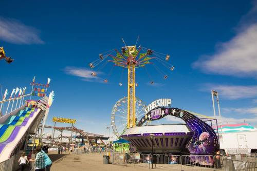 A vibrant amusement park scene featuring rides, colorful attractions, and a clear blue sky.