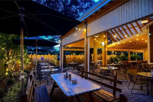 Cozy outdoor dining area with string lights, tables, and umbrellas, set in a warm evening ambiance.