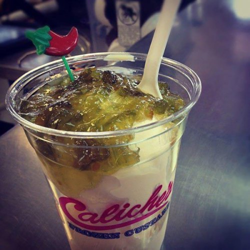 A cup of frozen custard topped with green jelly and a small chili pepper decoration.