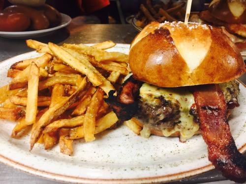 A juicy burger with melted cheese and bacon, served with crispy fries on a plate.