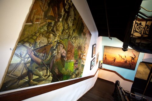 A staircase with colorful murals and paintings on the walls, showcasing various artistic styles and themes.