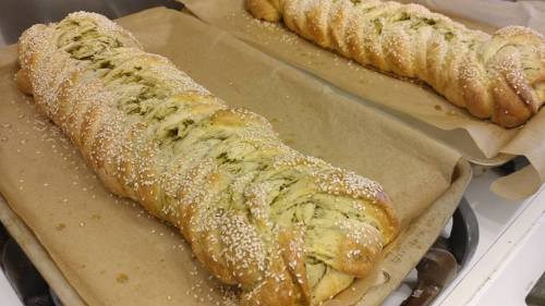 Two braided loaves of bread topped with sesame seeds, resting on parchment paper.