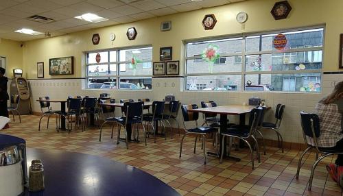 A cozy diner interior with empty tables, colorful decorations, and large windows letting in natural light.