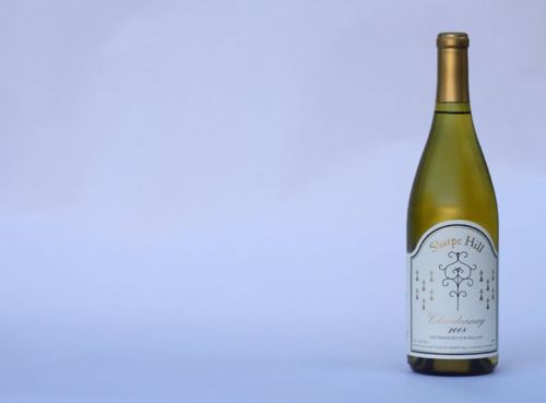 A bottle of Sharpe Hill Chardonnay 2006 stands against a light blue background.