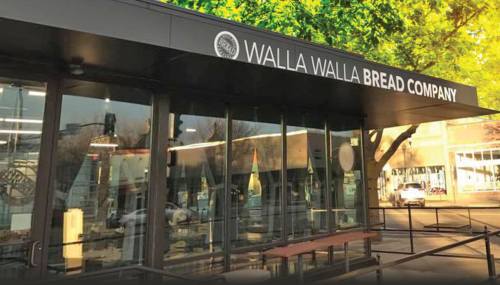 Exterior of Walla Walla Bread Company with large signage, showcasing a modern storefront and surrounding trees.