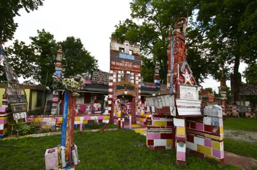 Colorful, whimsical structures made of bricks and signs in a vibrant outdoor setting with trees.