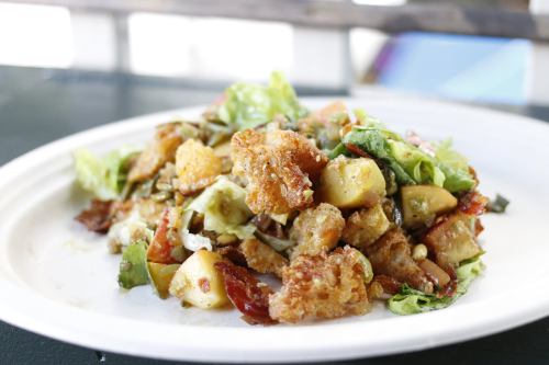 A colorful salad with greens, croutons, and various chopped vegetables served on a white plate.