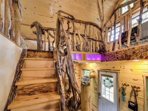 A cozy wooden interior with unique staircase railings and natural decor, leading to a bright, inviting space.