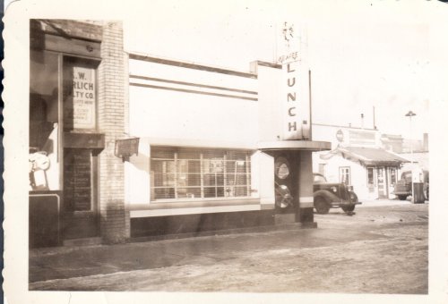 A vintage black-and-white photo of a diner named "Sea Breeze Lunch" with classic cars parked outside.