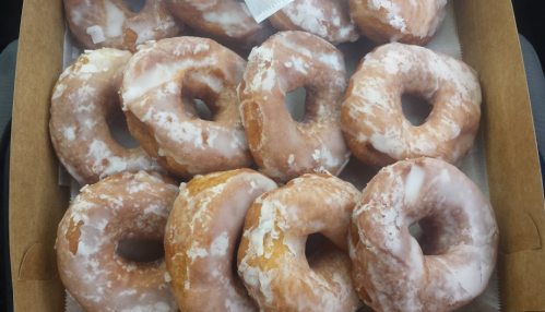 A box filled with glazed donuts, showcasing their light golden color and shiny icing.