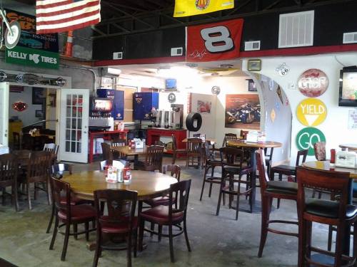 A casual dining area with wooden tables and chairs, decorated with racing memorabilia and traffic signs.