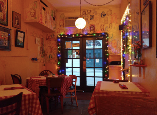 Cozy restaurant interior with checkered tables, colorful lights, and artistic wall murals.