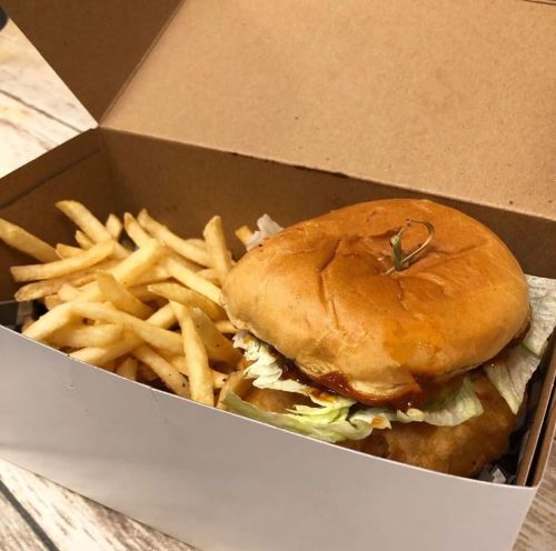 A boxed meal featuring a crispy chicken sandwich with lettuce and a side of golden French fries.