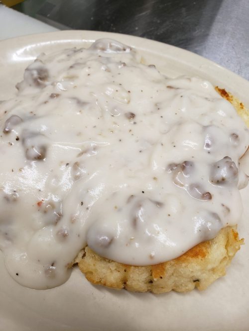 A plate of biscuits topped with creamy sausage gravy, showcasing a rich, smooth texture.