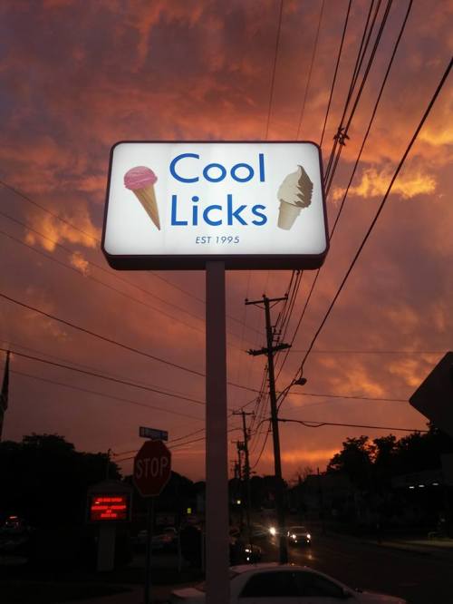 Sign for "Cool Licks" ice cream shop with a colorful sunset in the background, established in 1995.