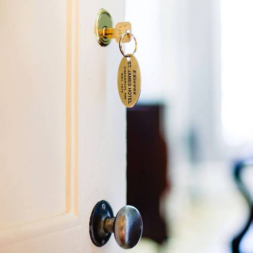 A close-up of a door with a key and tag labeled "EXCELSIOR HOTEL ST. JAMES" hanging from the lock.