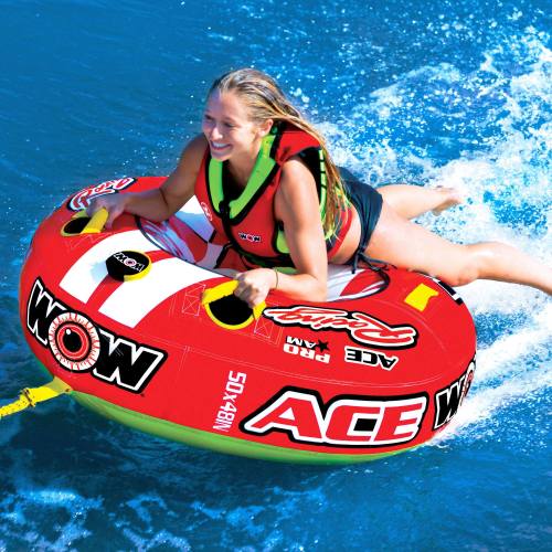 A smiling woman rides a red and yellow inflatable tube on blue water, enjoying a fun day of water sports.