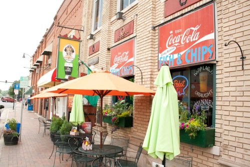 A cozy restaurant with outdoor seating, featuring colorful umbrellas and vintage Coca-Cola signage.