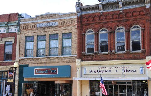 Historic buildings with brick facades, featuring shops like "Kokopelli Trails" and "Town & Country Antiques & More."