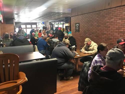 A busy restaurant interior with people seated at tables, chatting and enjoying their meals in a cozy atmosphere.