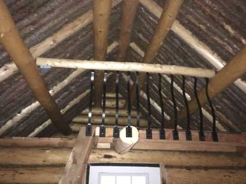 View of a wooden roof structure with exposed beams and metal brackets attached to the rafters.