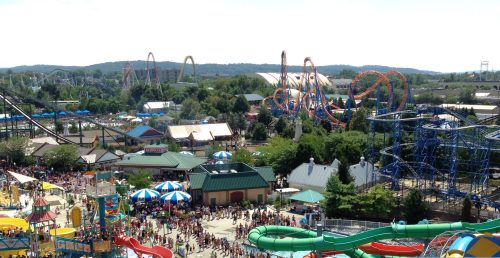 A vibrant amusement park scene with roller coasters, colorful rides, and a large crowd enjoying the attractions.