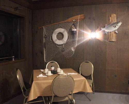 A cozy dining area with a wooden table, chairs, and nautical decor on the walls, including a fishing net and a fish.