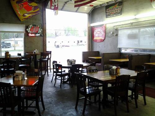 Interior of a casual dining space with wooden tables and chairs, featuring banners and a view of the outdoors.