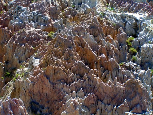 Colorful, rugged rock formations with sharp peaks and valleys, showcasing a mix of earthy tones and textures.