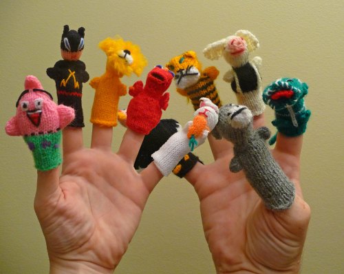 A hand with ten colorful knitted finger puppets, featuring various animal and character designs.