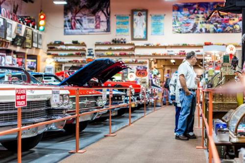 A vintage car museum with classic cars on display and visitors admiring the exhibits.