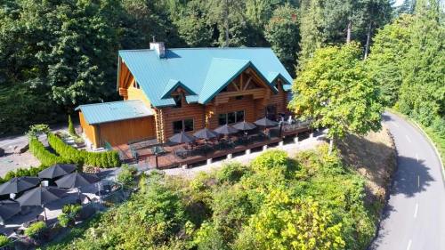Aerial view of a log cabin-style restaurant surrounded by trees and outdoor seating along a winding road.