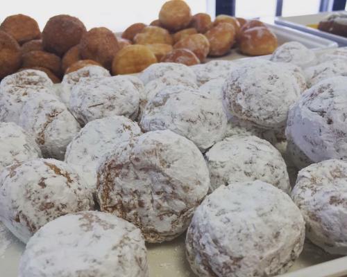A close-up of powdered sugar-coated cookies, with various other pastries in the background.