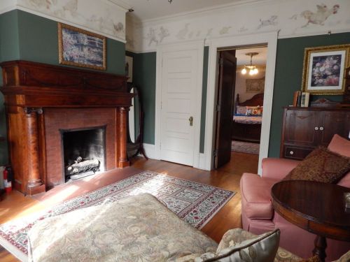 Cozy room with a fireplace, pink furniture, and decorative wall art, featuring a doorway to another room.