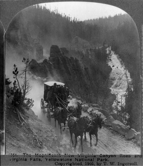 A horse-drawn carriage travels along a rugged road near Virginia Falls in Yellowstone National Park, circa 1905.