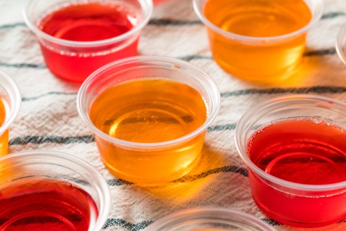 Colorful gelatin cups in clear containers, arranged on a striped cloth.