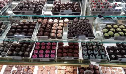 A display case filled with various chocolate truffles and confections in different shapes and colors.