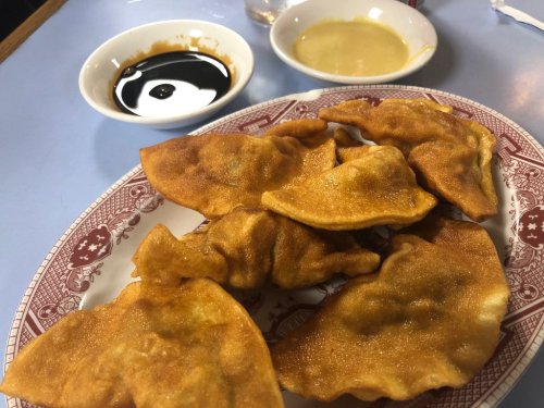 A plate of golden-brown fried dumplings with dipping sauces on the side.