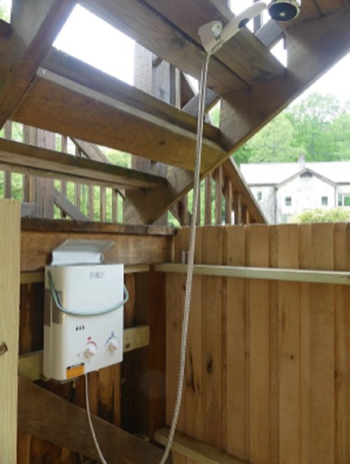 Outdoor shower installed on a wooden structure, featuring a showerhead and controls mounted on a fence.