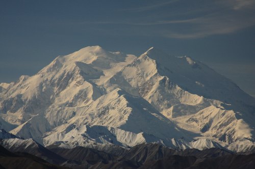 Snow-capped mountain peaks under a clear sky, showcasing rugged terrain and dramatic slopes.