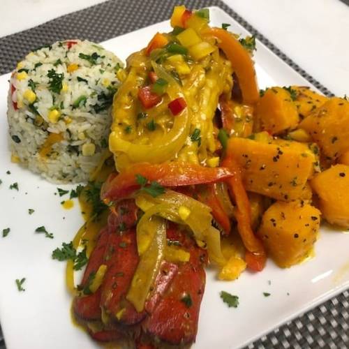 A plate featuring lobster in a colorful sauce, served with rice and diced butternut squash.