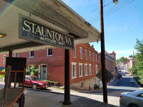 Sign for Staunton, VA, with a view of a street lined with historic buildings and a parked car. Altitude: 1395 ft.